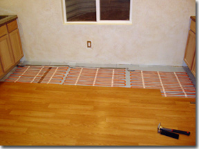 Floor heating element being installed under hardwood floor.